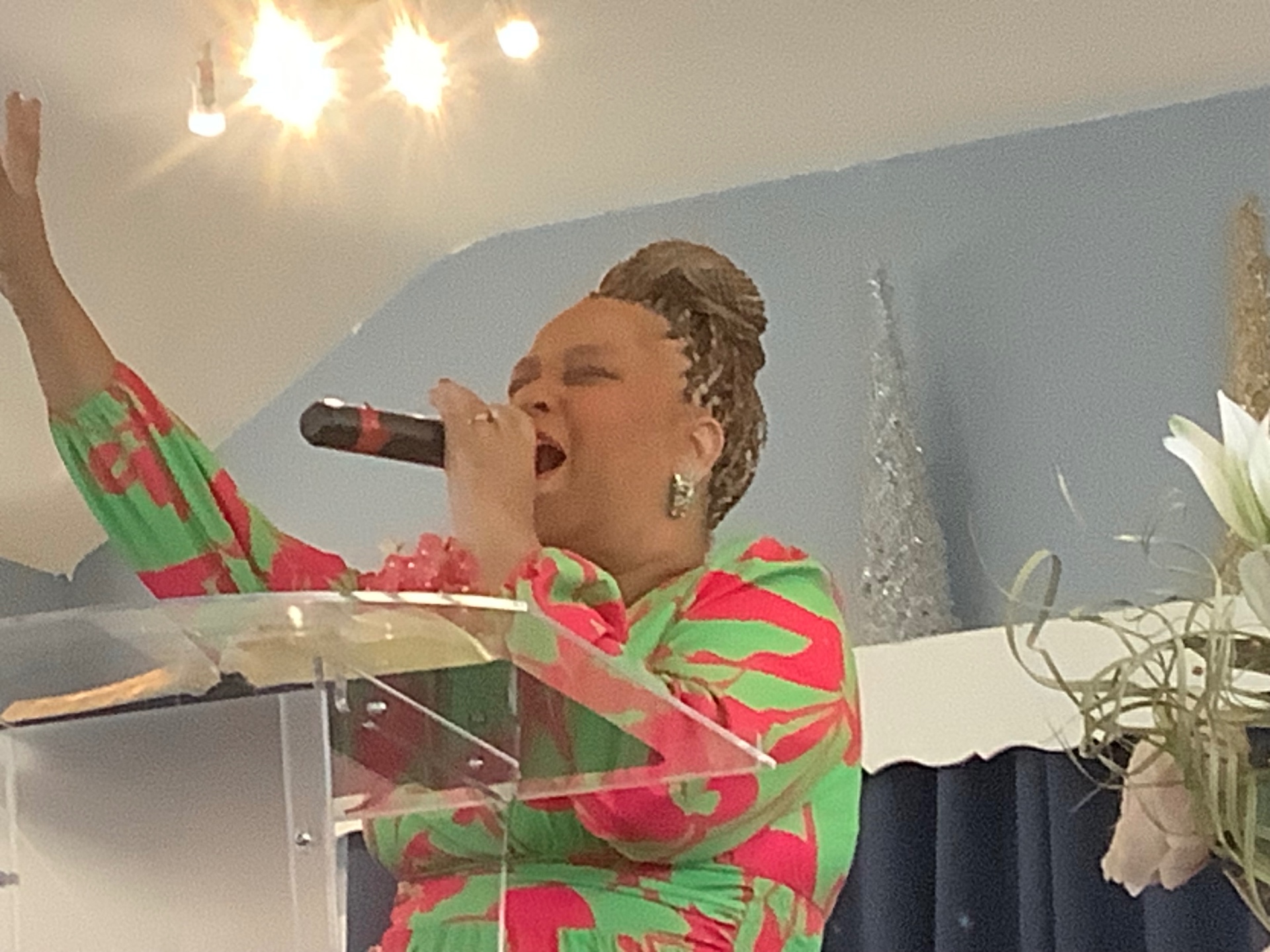 Worship leader singing with hand raised at the pulpit